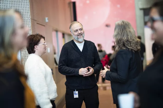 På bilden syns en grupp människor som står och samtalar. 